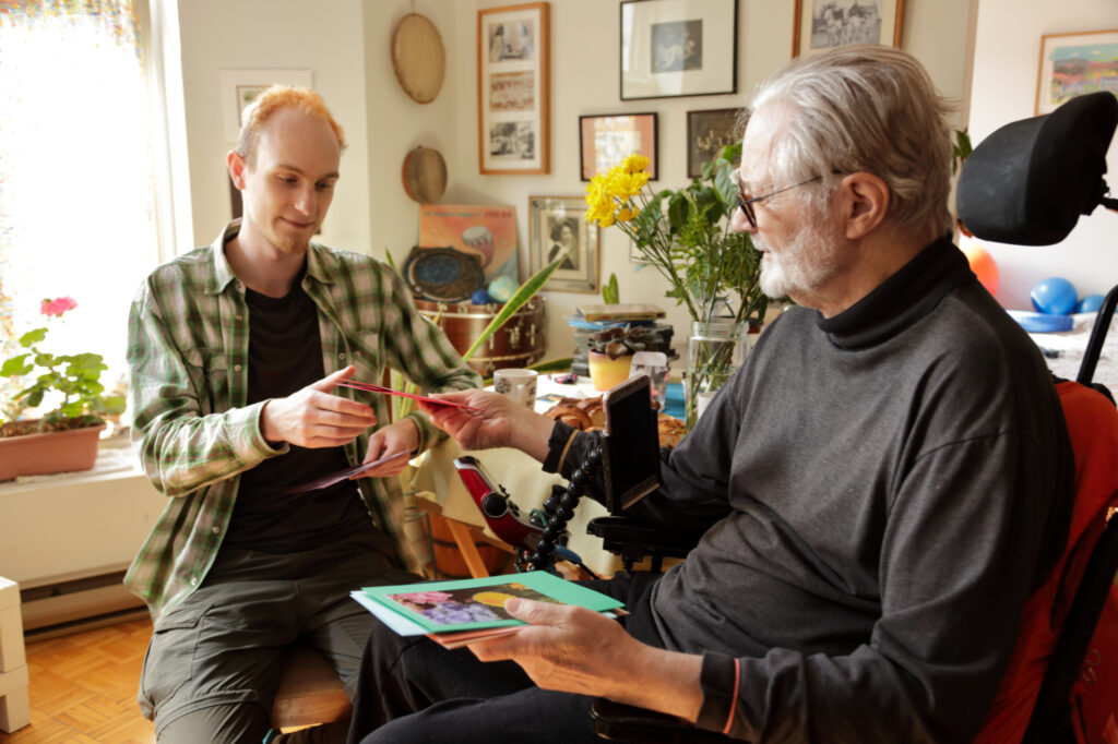 A young man and an older man look at handmade cards together.