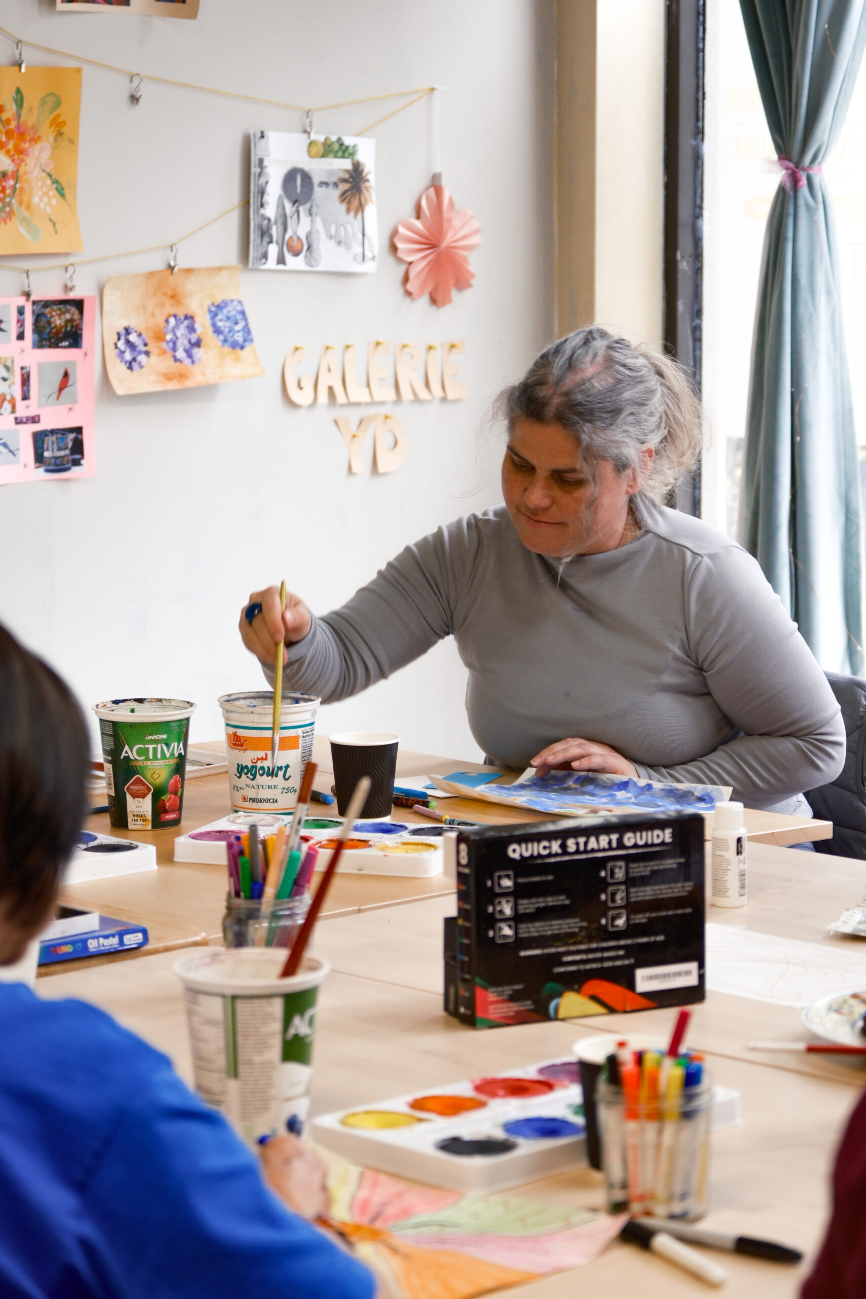 A woman paints in a sunny room